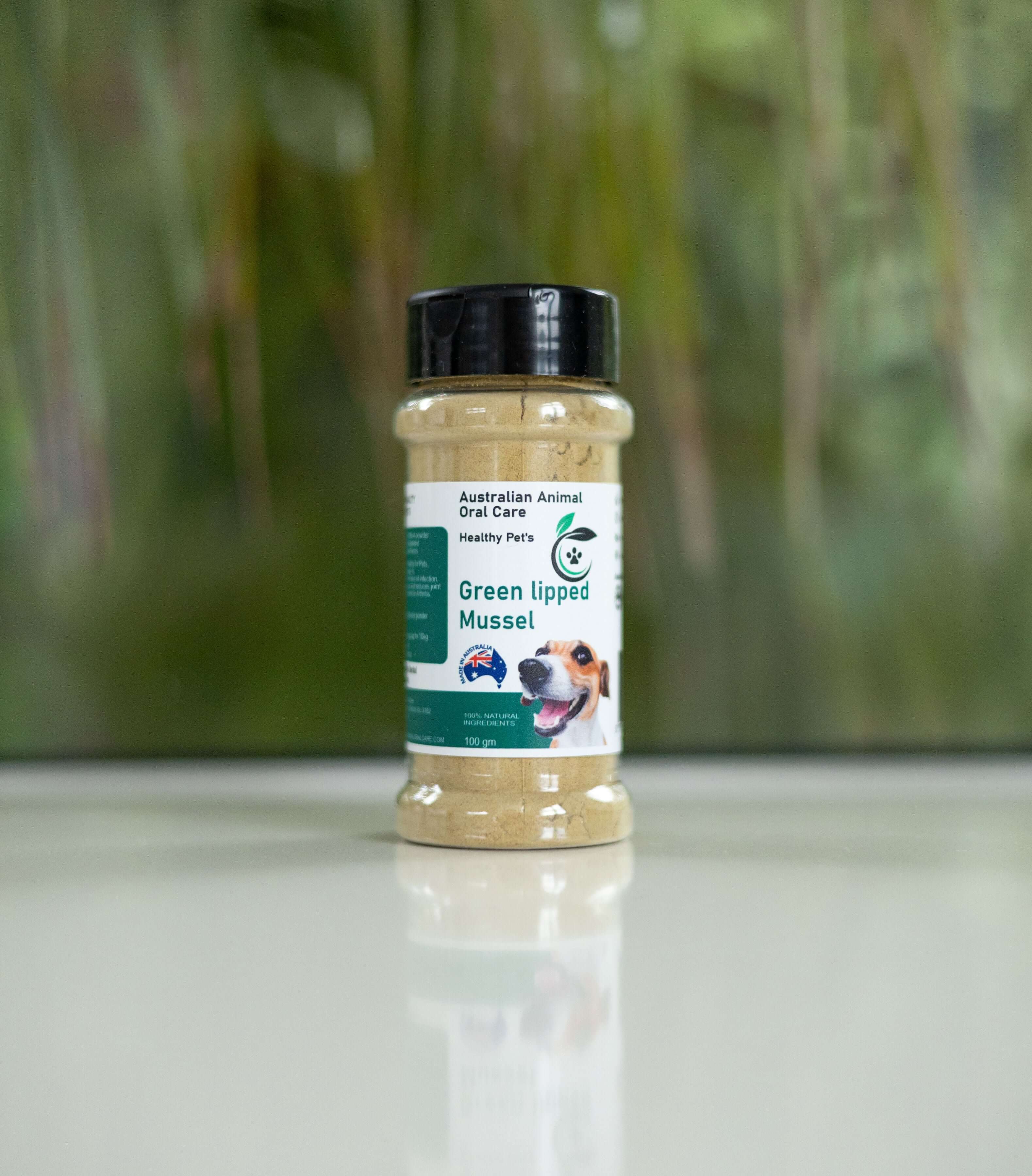 Bottle of Green Lipped Mussel supplement on a white surface with a blurred green background